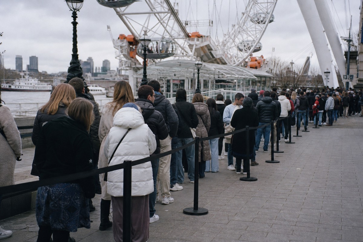 A long queue line on the London Eye plaza in overcast midday light