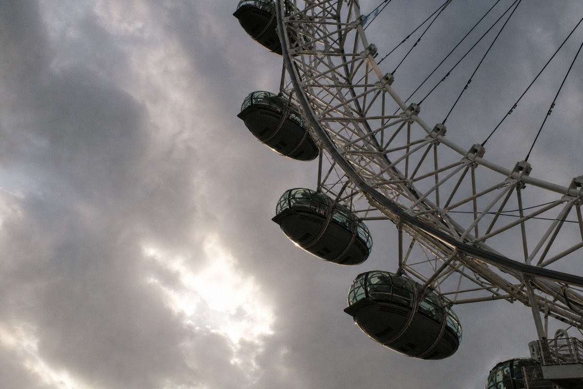 The London Eye's capsules seen from below against a stormy sky breaking to sun