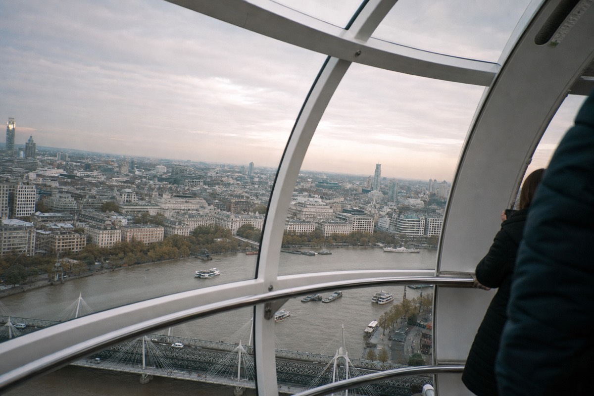 Looking out through a London Eye capsule's curved glass wall at the river and rooftops below